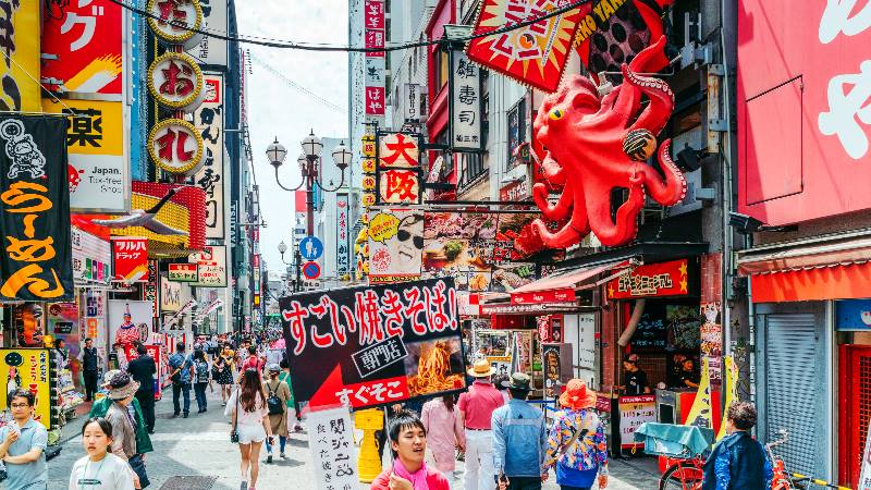 People-walking-through-busy-Osaka-street-with-many-food-signs-on-buildings-at-the-Rugby-World-Cup