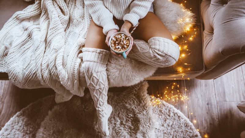 Lady-sitting-on-a-sofa-wearing-long-woollen-socks-hygge-style