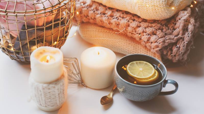 Hygge-concept-candles-drink-and-woollen-blankets