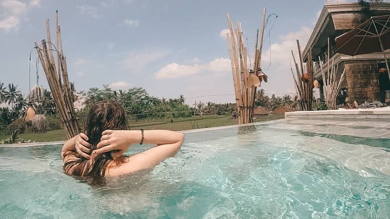 Female-brushing-her-hair-back-in-swimming-pool-on-a-travelling-solo-trip