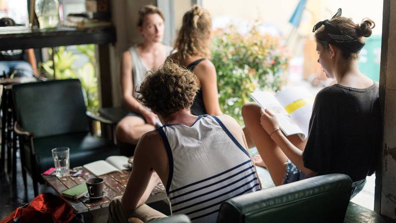 Group-of-young-people-including-a-female-solo-traveller-in-a-youth-hostel-relaxing