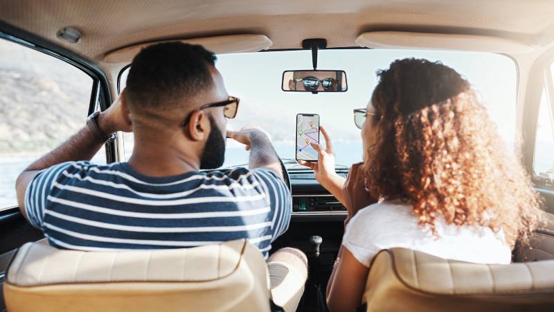 Two-people-in-a-car-searching-directions-on-the-phone-travel-apps-2020