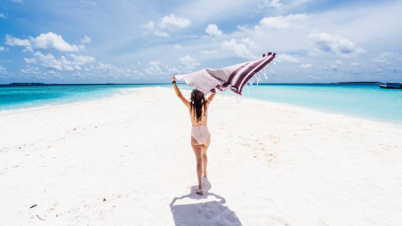 woman-waving-a-towel-on-sandy-beach