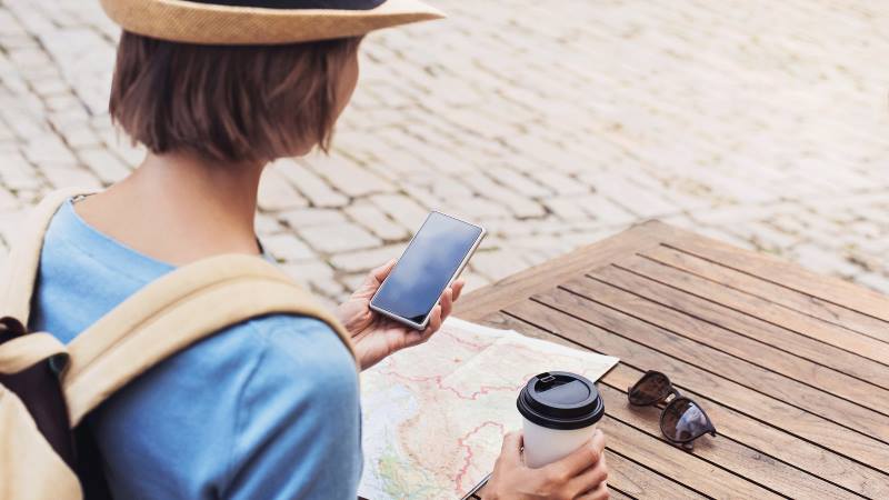 Lady-with-coffee-sitting-at-a-cafe-table-with-map-and-phone-out